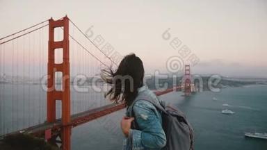 年轻女创意工携背包散步看史诗般的风景，名落日金门桥在大风中..